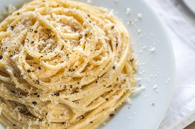 A dish of spagetti topped with black pepper
